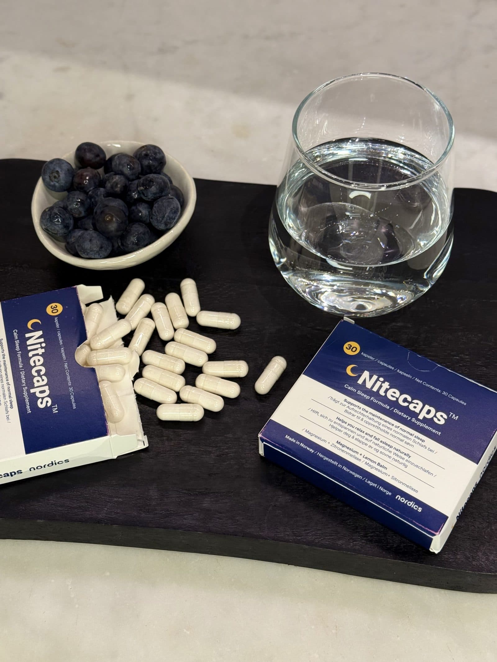 Complément alimentaire NiteCaps sans mélatonine, avec des gélules et un verre d’eau.
